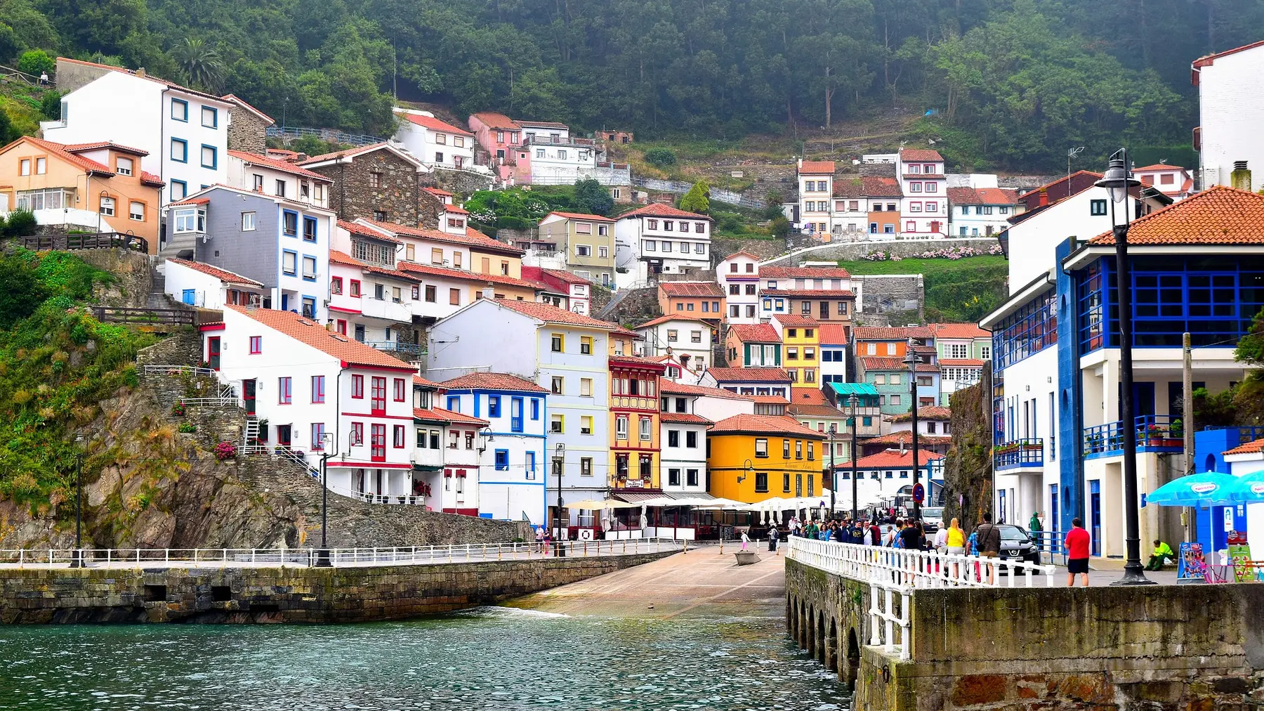 El muelle de Cudillero y la bocana del puerto, con gente paseando